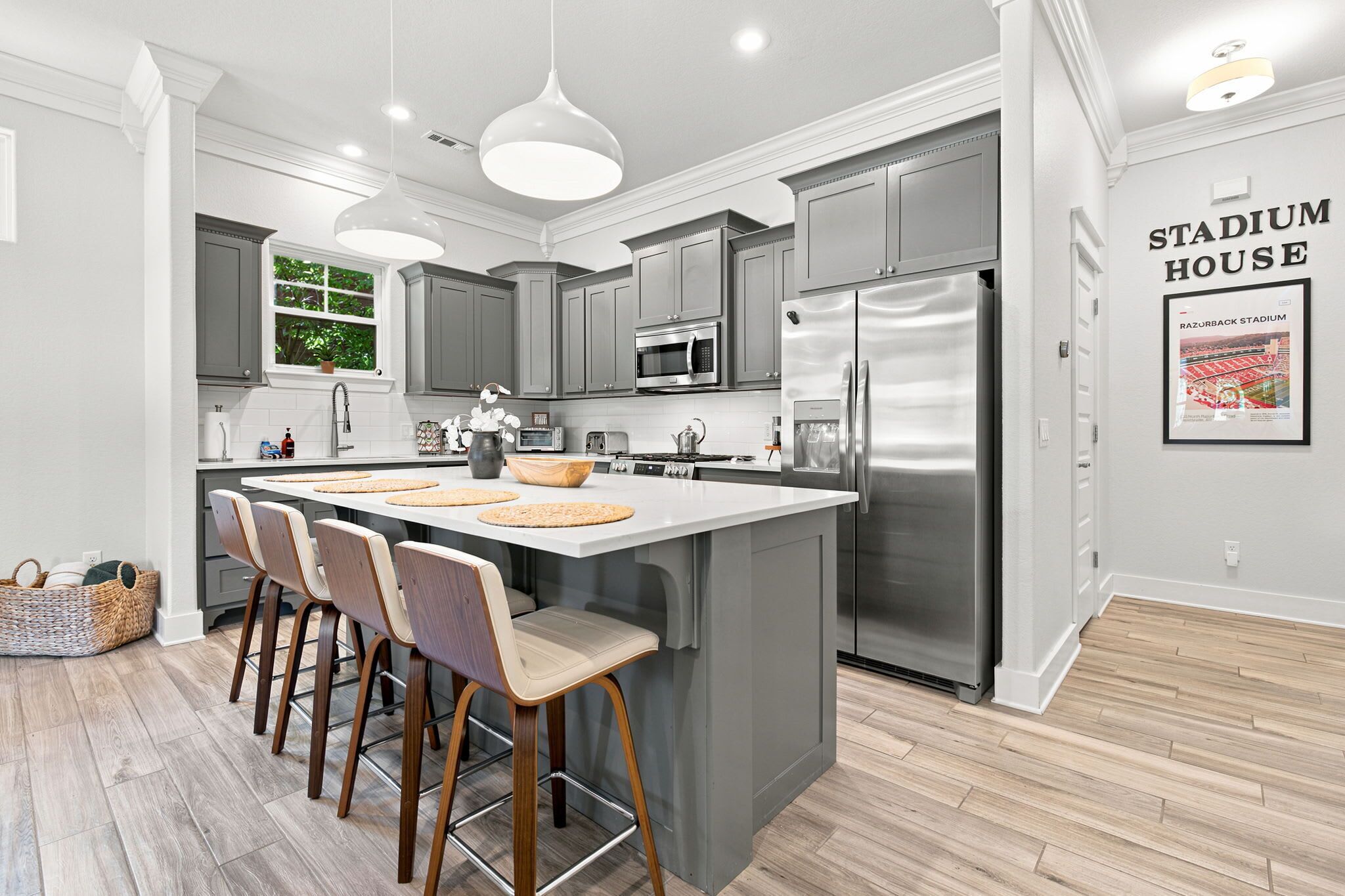 A modern kitchen with grey cabinets, stainless steel appliances, and a central island with bar stools.