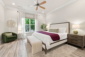 A bedroom with a bed, a nightstand, a chair, a window, and a ceiling fan.