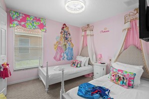 Een slaapkamer in roze tinten, met een bed, nachtkastje, raam met zonwering en een muurschildering.