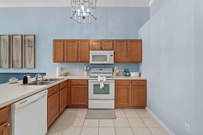 A kitchen with wooden cabinets, a white stove, a microwave, and a dishwasher. - Family Getaway with Pool and Game Room (Davenport)