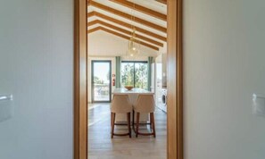 Une cuisine moderne avec un coin repas, des poutres en bois au plafond et une grande fenêtre.