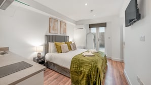 A modern hotel room with a bed, bedside table, lamp, and a flat-screen TV mounted on the wall. - Standard Studio With Terrace In Knightsbridge (London)