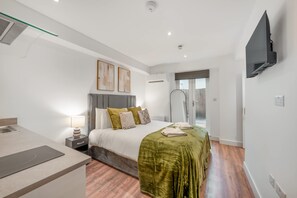 A modern hotel room with a bed, bedside table, lamp, and a flat-screen TV mounted on the wall. - Standard Studio With Terrace In Knightsbridge (London)