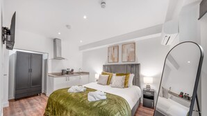 A hotel room with a bed, a wardrobe, a kitchenette, and a mirror. - Standard Studio With Terrace In Knightsbridge (London)