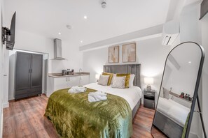 A hotel room with a bed, a wardrobe, a kitchenette, and a mirror. - Standard Studio With Terrace In Knightsbridge (London)