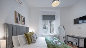 Een moderne hotelkamer met een bed, bureau, stoel, televisie en raam met uitzicht.