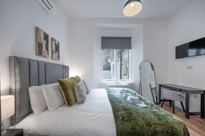 Ein modernes Hotelzimmer mit Bett, Schreibtisch, Stuhl, Fernseher und einem Fenster mit Aussicht.