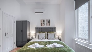 Een slaapkamer met een bed, een kledingkast, een raam en een airconditioning.