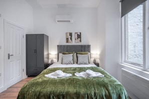 Ein Schlafzimmer mit Bett, Kleiderschrank, Fenster und Klimaanlage.