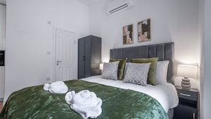 Een hotelkamer met een bed, een kledingkast, een nachtkastje met een lamp en een airconditioning.