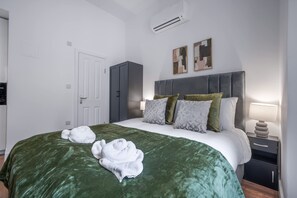Ein Hotelzimmer mit einem Bett, einem Kleiderschrank, einem Nachttisch mit Lampe und einer Klimaanlage.