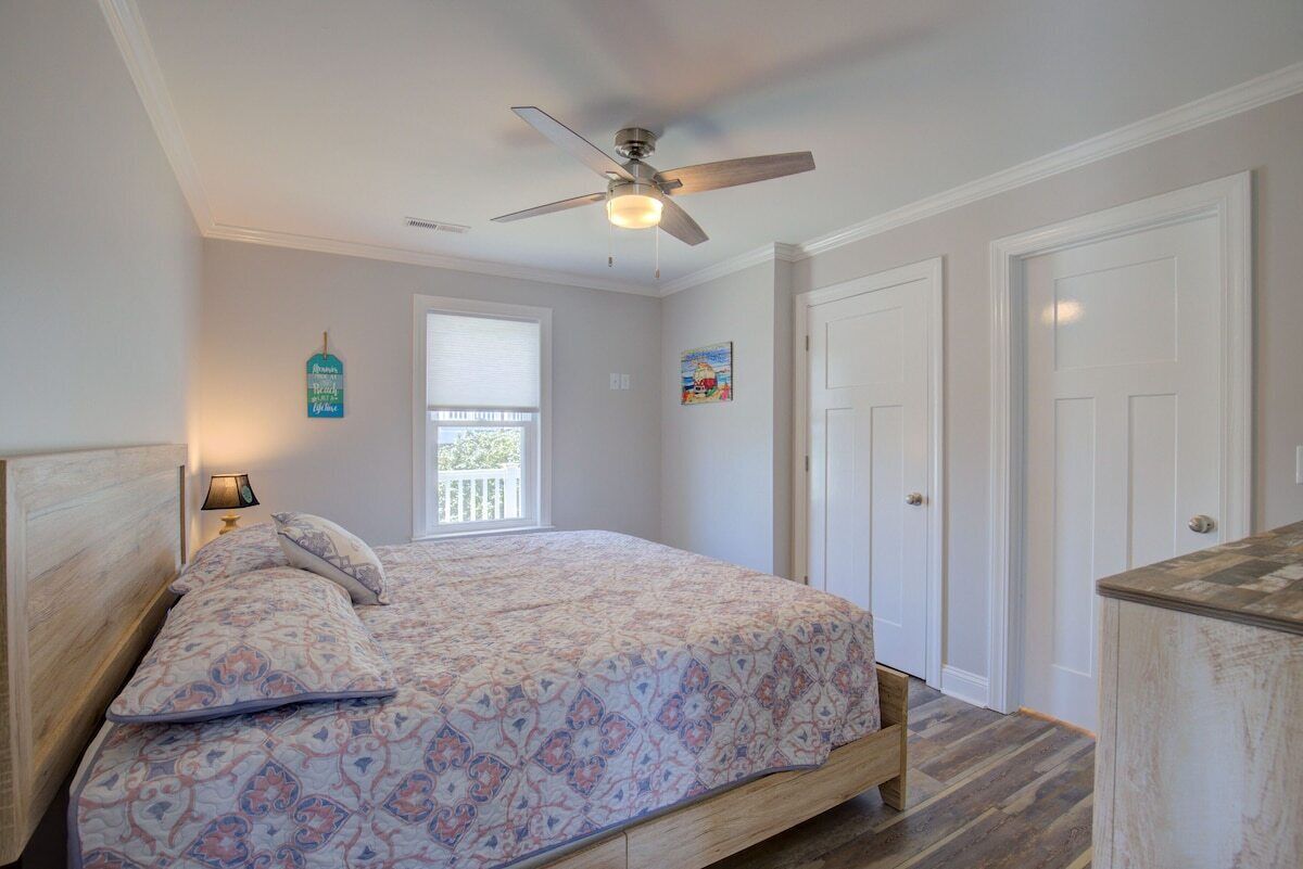 Un dormitorio con cama, ventilador de techo, ventana y puerta.