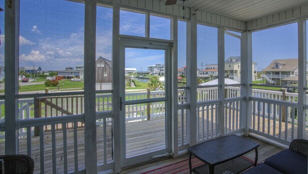 A covered porch with a ceiling fan, a table, and chairs. - Canalfront dock with hot tub and views (North Topsail Beach)