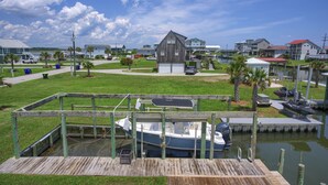 A marina with a dock, a boat, and houses in the background. - Canalfront dock with hot tub and views (North Topsail Beach)