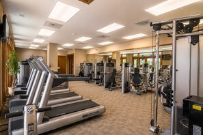 Ein Fitnessstudio mit Laufbändern, Kraftgeräten und einer Spiegelwand.