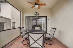 A balcony with a table and chairs, a ceiling fan, and a clock on the wall. - Cozy 5BD 3,5BA Clermont Villa/Heated Pool/Parks (Clermont)