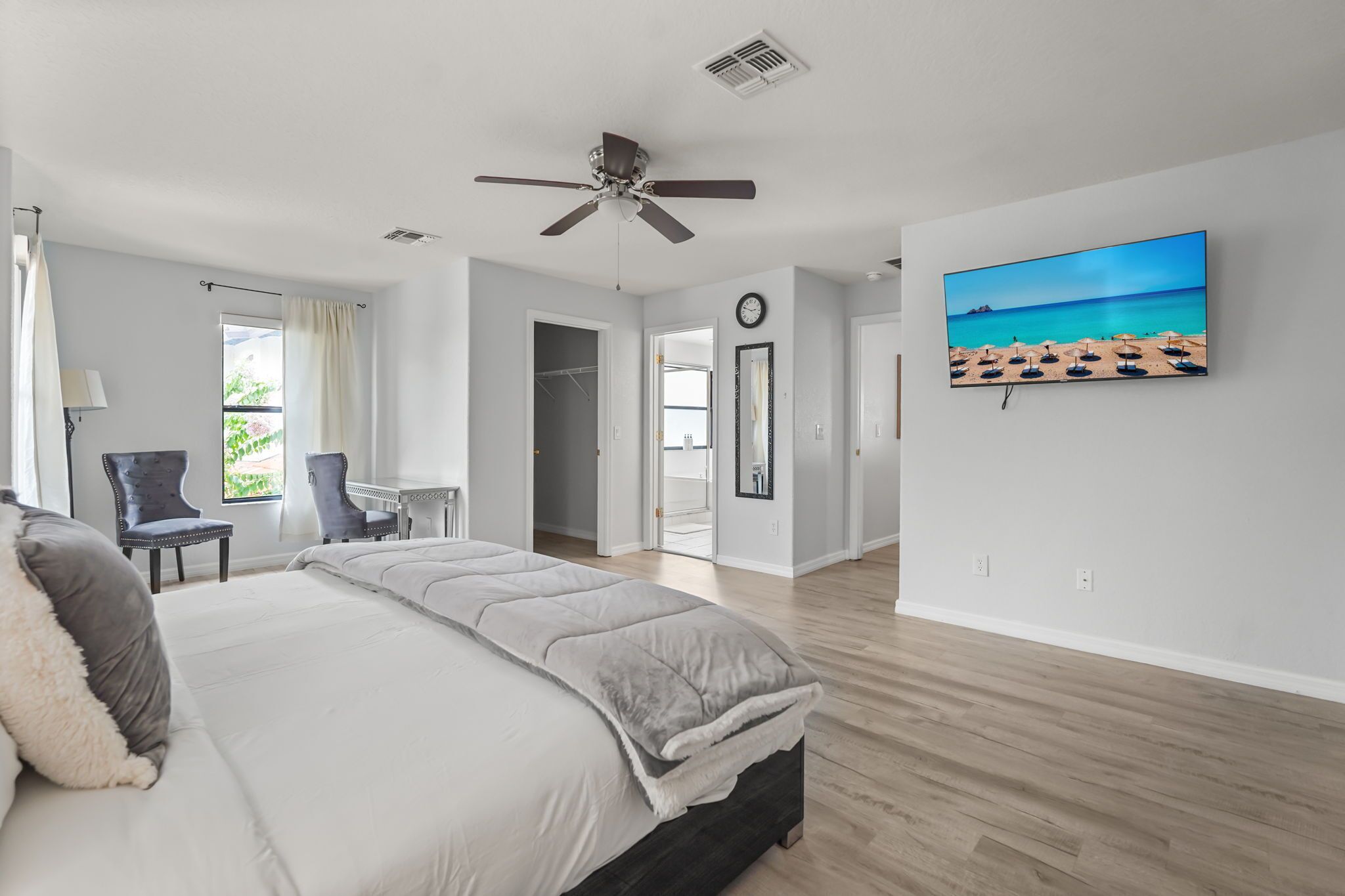 Ein Schlafzimmer mit Bett, Deckenventilator, Fernseher und Blick ins Freie.