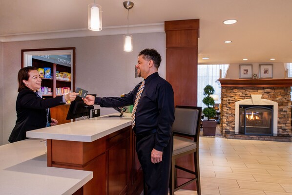 A reception desk with a counter, a fireplace, and a display of candy/snacks in the background.