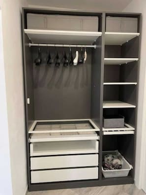 A walk-in closet with multiple shelves, drawers, and hanging space.