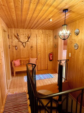 Un intérieur en bois avec un banc, un lustre et des éléments de décoration fixés au mur.