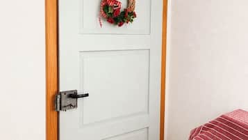 Una puerta blanca con marco de madera, un picaporte negro y un lazo rojo y blanco a cuadros.