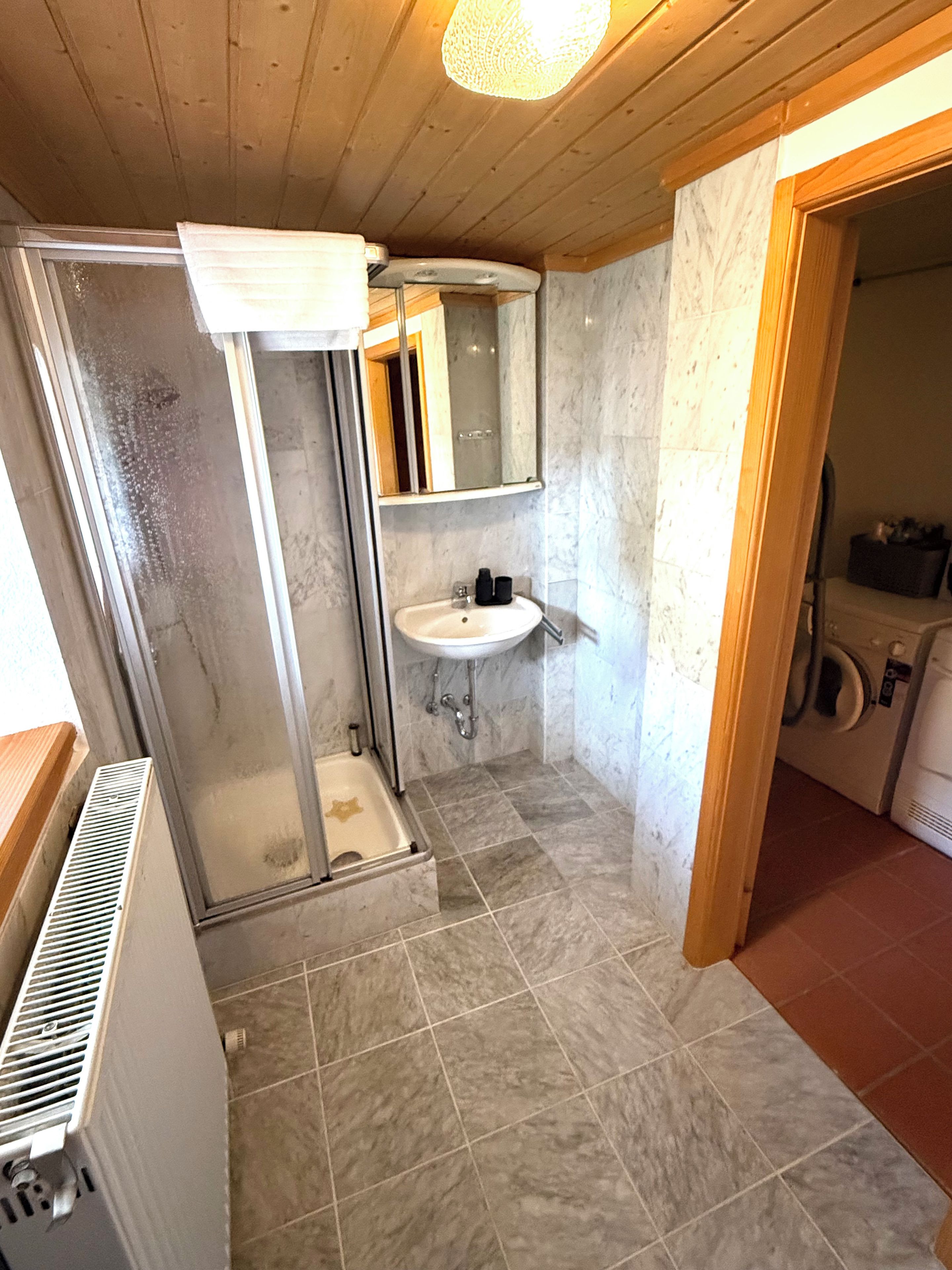 A bathroom with a shower, sink, and a mirror.