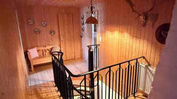 Interior de madera con una escalera, un banco y una calavera de ciervo montada en la pared.
