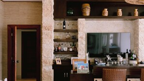 A living room with a fireplace, a television, and a bar area with stools. - Luxury9BR Villa39 Juanillo Private Beach (Punta Cana)