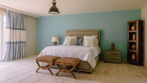 A bedroom with a bed, bedside tables, a nightstand, a lamp, and a wooden cabinet. - Luxury9BR Villa39 Juanillo Private Beach (Punta Cana)