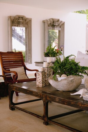 Una habitación con una silla de madera, una mesa de piedra y una planta en maceta.