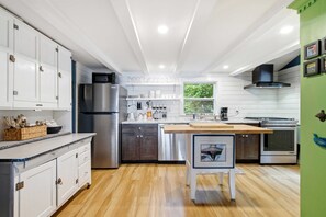 Uma cozinha moderna com armários brancos, eletrodomésticos de aço inoxidável e uma ilha de madeira.