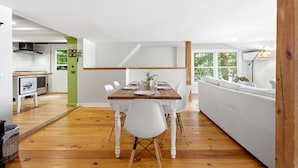A dining area with a wooden table, white chairs, and a white sofa. - Highland Lake Cottage/Waterfront/Dock/Kayaks (Windham)
