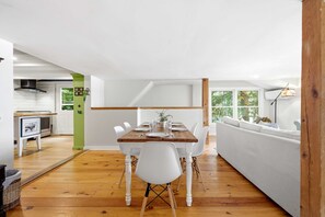 A dining area with a wooden table, white chairs, and a white sofa. - Highland Lake Cottage/Waterfront/Dock/Kayaks (Windham)