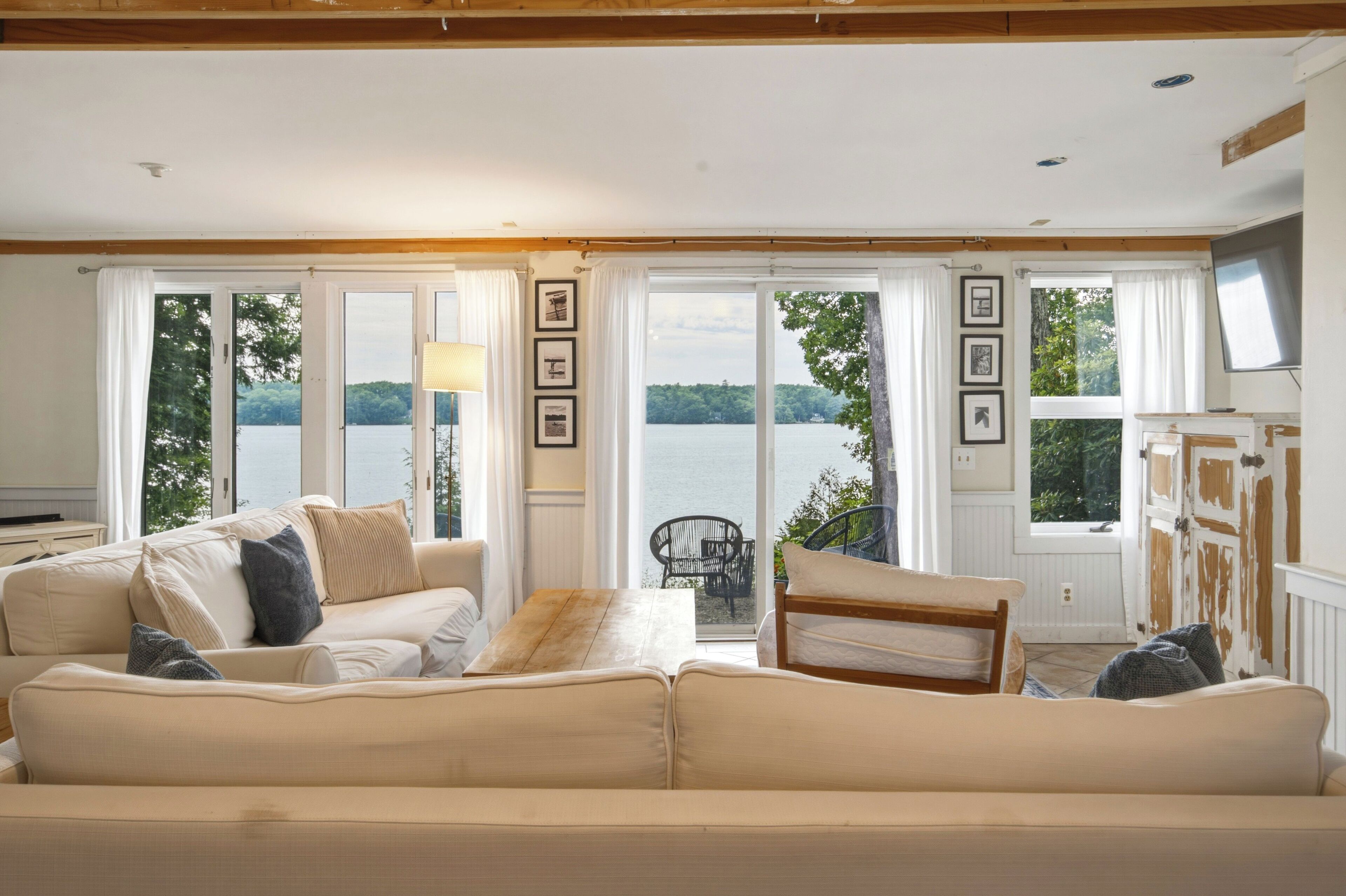 A living room with a sofa, a coffee table, and a view of a lake through large windows.