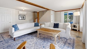 A living room with a white sofa, a wooden coffee table, and a patterned rug. - Highland Lake Cottage/Waterfront/Dock/Kayaks (Windham)