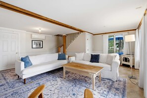 A living room with a white sofa, a wooden coffee table, and a patterned rug. - Highland Lake Cottage/Waterfront/Dock/Kayaks (Windham)