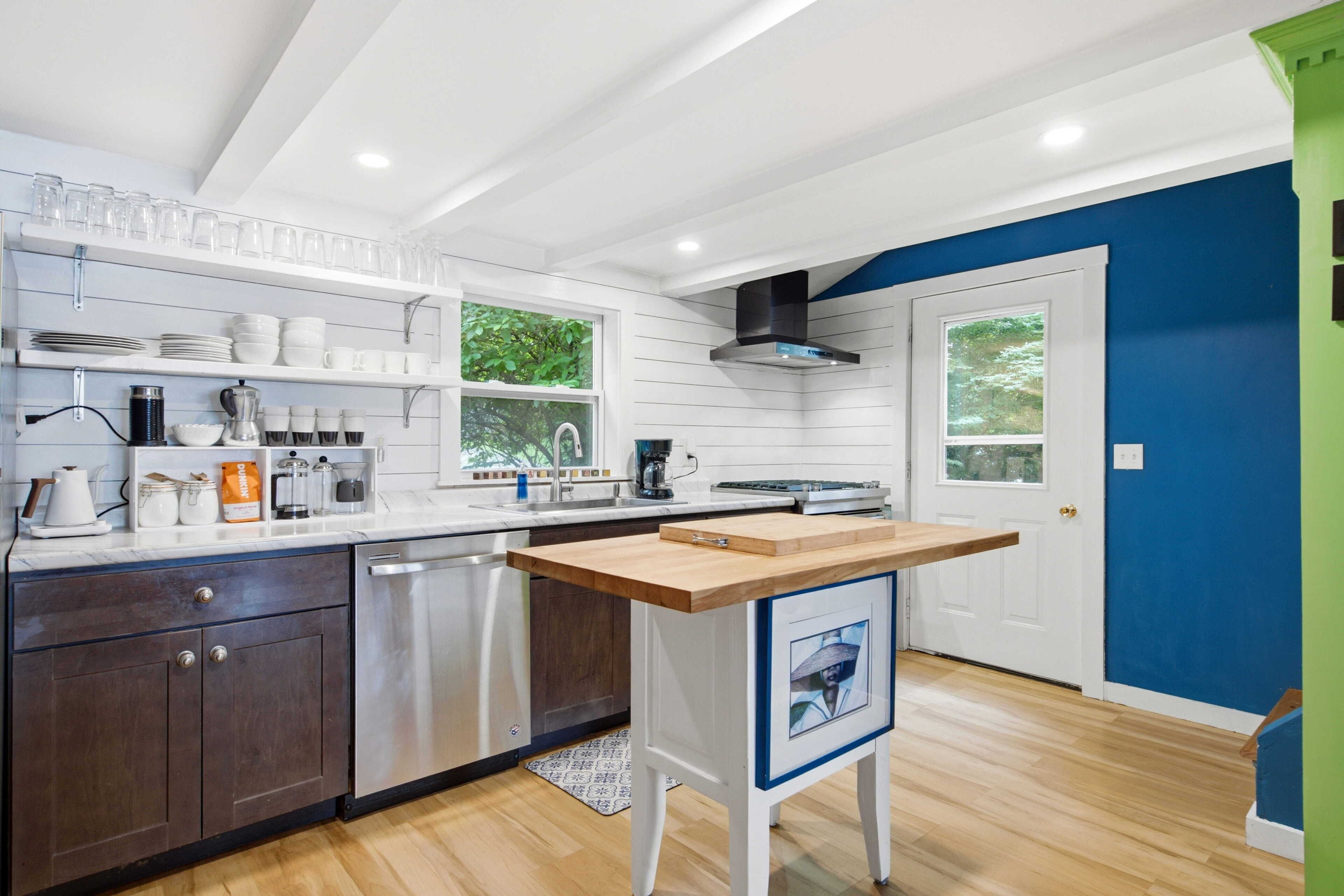 A modern kitchen with white cabinetry, a wooden countertop, and a built-in dishwasher.