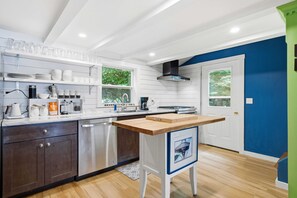 A modern kitchen with white cabinetry, a wooden countertop, and a built-in dishwasher. - Highland Lake Cottage/Waterfront/Dock/Kayaks (Windham)