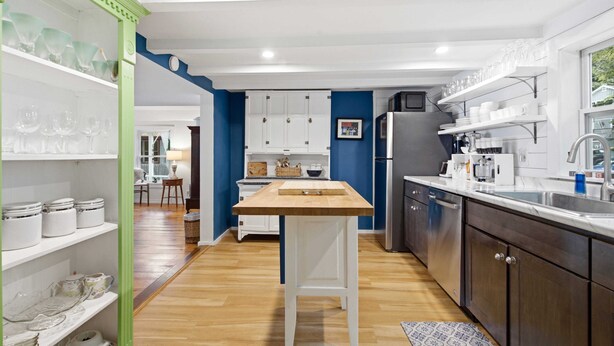 A modern kitchen with white cabinets, a wooden bar stool, and a stainless steel refrigerator. - Highland Lake Cottage/Waterfront/Dock/Kayaks (Windham)
