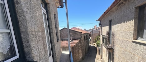 A narrow alleyway between buildings with stone walls and tiled roofs.