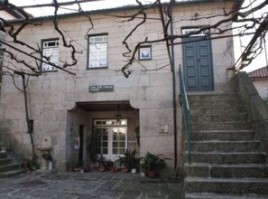A stone building with a staircase leading to a door, surrounded by potted plants. - Casa João Fidalgo- 4 bedroom house in Soajo, Arcos de Valdevez (Soajo, Arcos de Valdevez)
