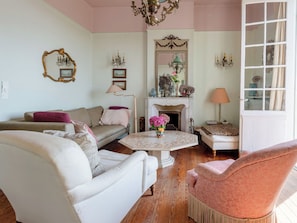 A living room with a sofa, armchair, fireplace, and decorative items. - Maison Rose by Interhome (Deauville-Trouville)