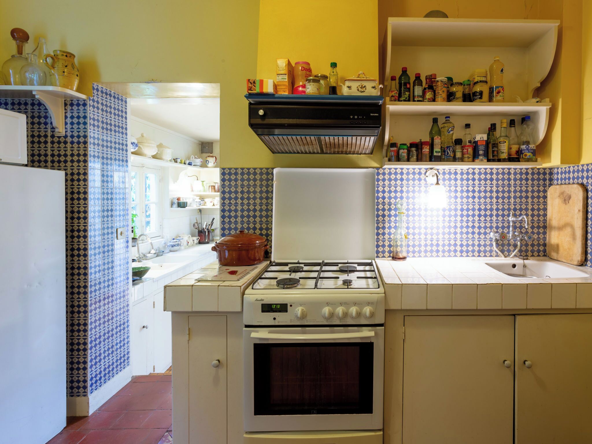 Uma cozinha compacta com fogão a gás, forno e diversos utensílios de cozinha nas bancadas.
