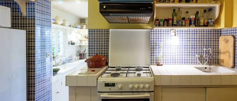 Uma cozinha compacta com fogão a gás, forno e diversos utensílios de cozinha nas bancadas.