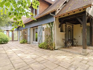 A courtyard with a tiled floor, a covered seating area, and a building with a tiled roof and wooden shutters. - Le Chant d'Azif by Interhome (Deauville-Trouville)
