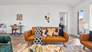 A modern living room with a leather sofa, a glass coffee table, and a desk with a chair. -     Spacious Katy TX  one story Home / 4 Bedrooms + Hot Tub (Katy)