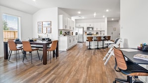 A modern kitchen with white cabinets, a dining area with wooden chairs, and a bar area with stools. -     Spacious Katy TX  one story Home / 4 Bedrooms + Hot Tub (Katy)