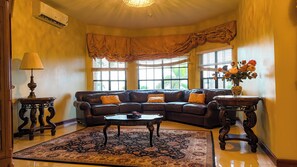 A living room with a leather sofa, a coffee table, a rug, a lamp, and a vase with flowers. - 7-Bedroom Villa with Pool, Ocean Views & Premium Amenities. (St. Ann)
