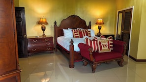 Un dormitorio con una cama grande, dos mesitas de noche, un aparador y un sillón rojo.