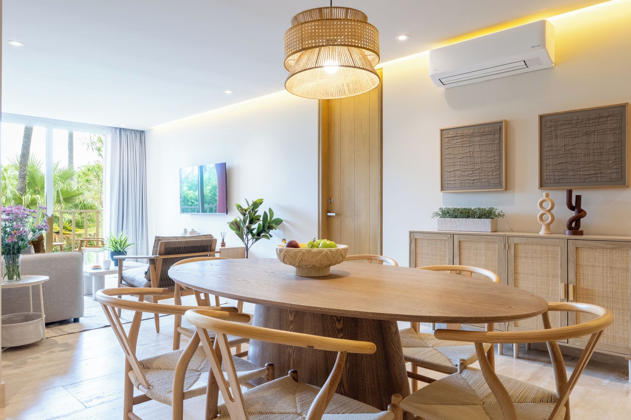 Un espace repas moderne avec une table ronde en bois, des chaises en osier et un luminaire central.